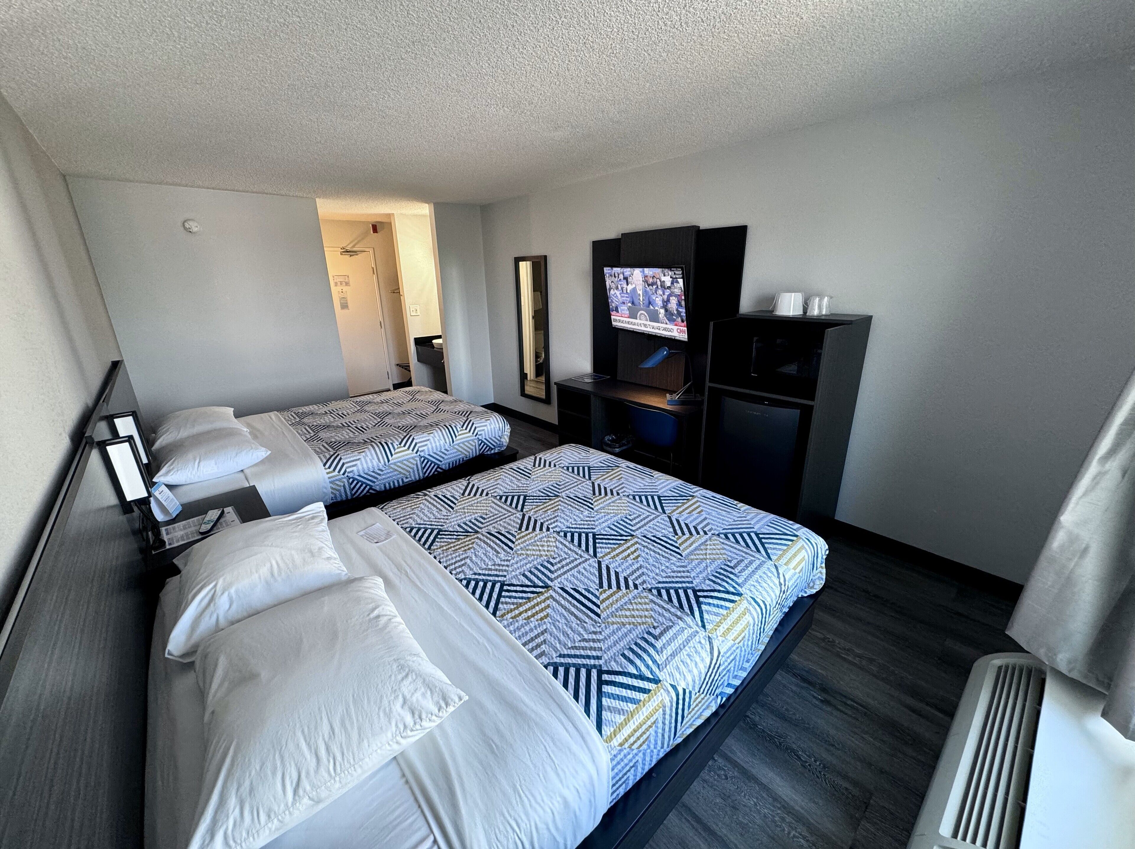 A hotel room with two beds, a TV, a desk, and a wardrobe.