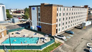 Un hotel de varios pisos con zona de piscina, estacionamiento y vistas del entorno.