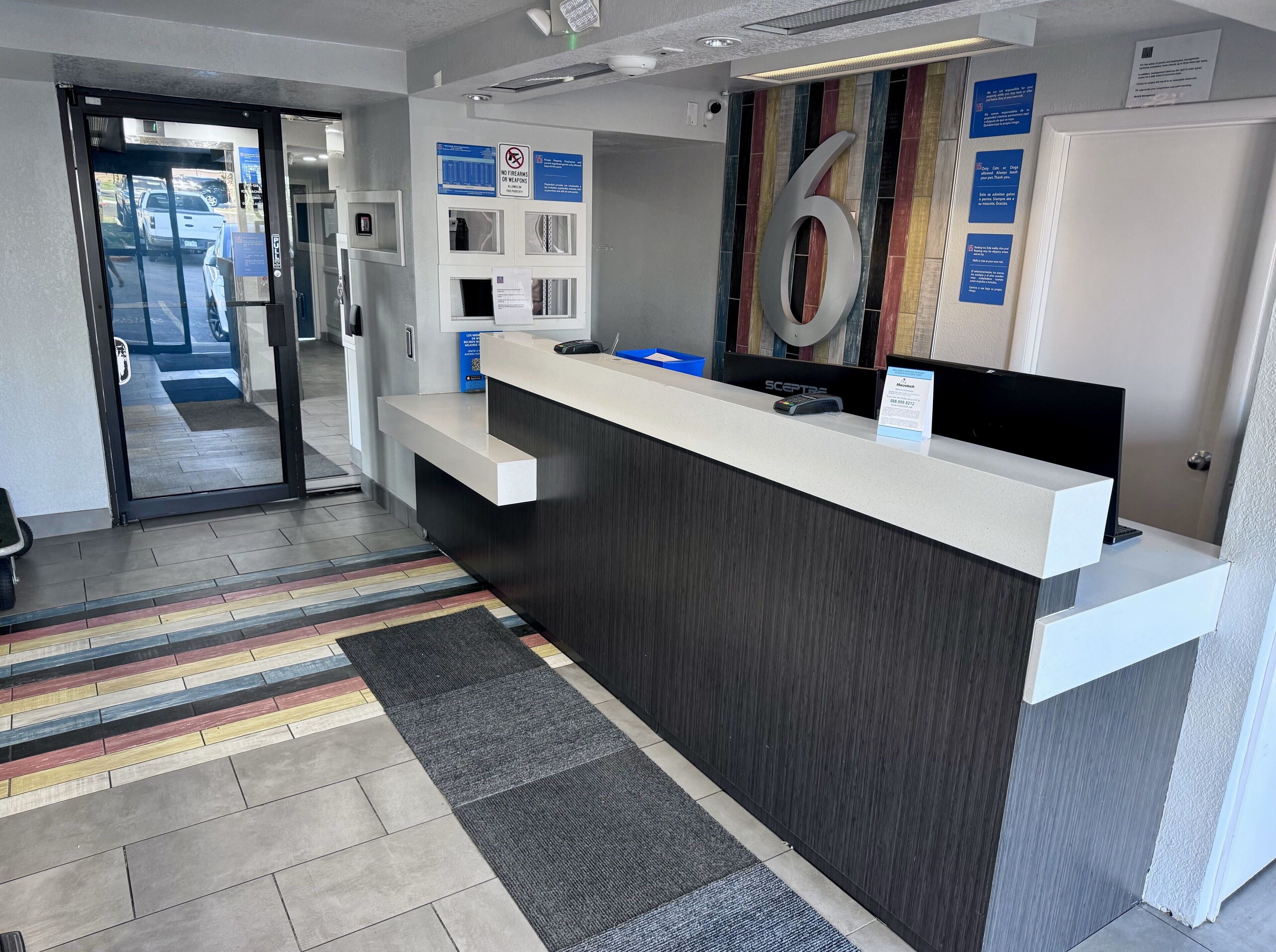 A reception area with a modern design, including a reception desk, a large number '6' sign, and informational posters on the wall.
