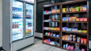 A vending machine and a shelf stocked with snacks and beverages.