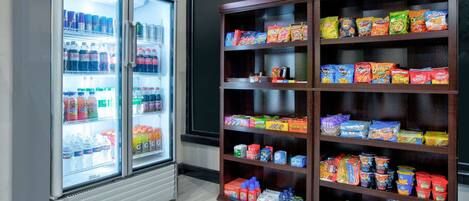 A vending machine and a shelf stocked with snacks and beverages.