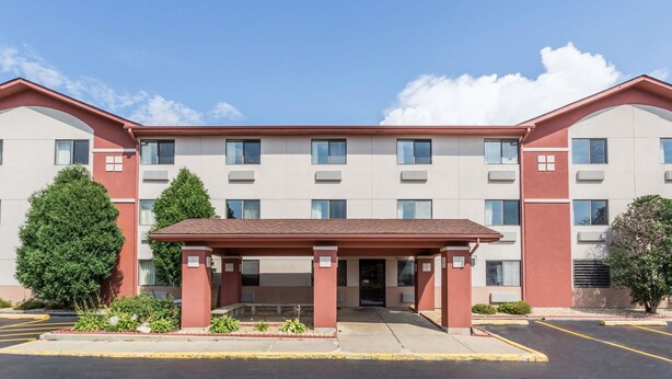A multi-story hotel with a central entrance, air conditioning units, and a parking lot. - Super 8 by Wyndham St. Charles (St. Charles)