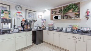 A kitchen with a coffee machine, a trash bin, and a microwave. - Super 8 by Wyndham St. Charles (St. Charles)