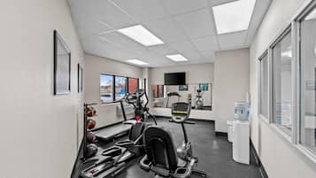 A gym with treadmills, elliptical machines, and a water dispenser.