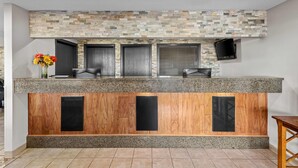 A reception area with a stone mosaic wall, a wooden panel design, and a flat-screen TV mounted on the wall. - Days Inn & Suites by Wyndham Des Moines Airport (Des Moines)