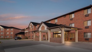 A brick building with a covered entrance and a car parked in front. - Days Inn & Suites by Wyndham Des Moines Airport (Des Moines)