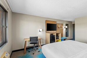 A hotel room with a bed, a desk with a chair, a television, and a wardrobe. - Days Inn & Suites by Wyndham Des Moines Airport (Des Moines)