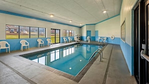 An indoor swimming pool with clear windows, white chairs, and a blue and white color scheme. - Days Inn & Suites by Wyndham Des Moines Airport (Des Moines)