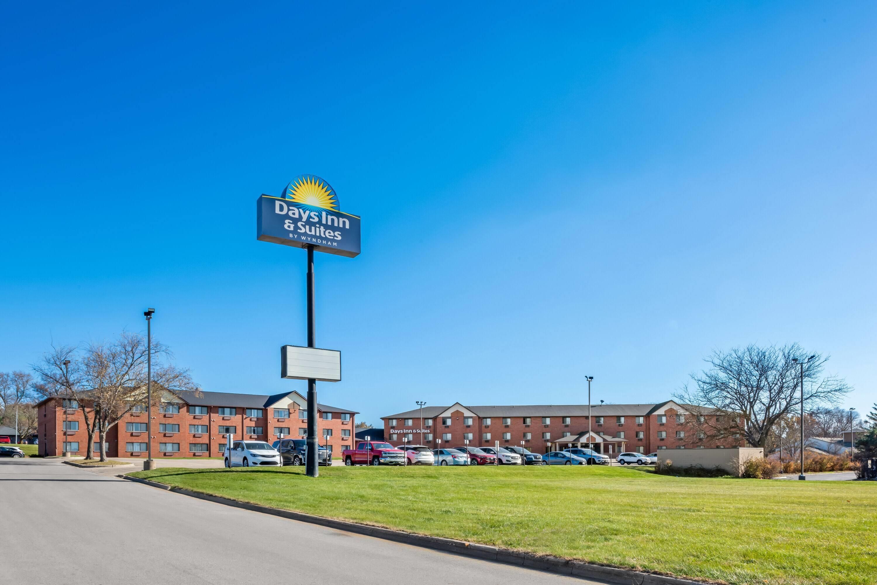 Señalización de Days Inn & Suites, un estacionamiento y un edificio con varios pisos y ventanas.