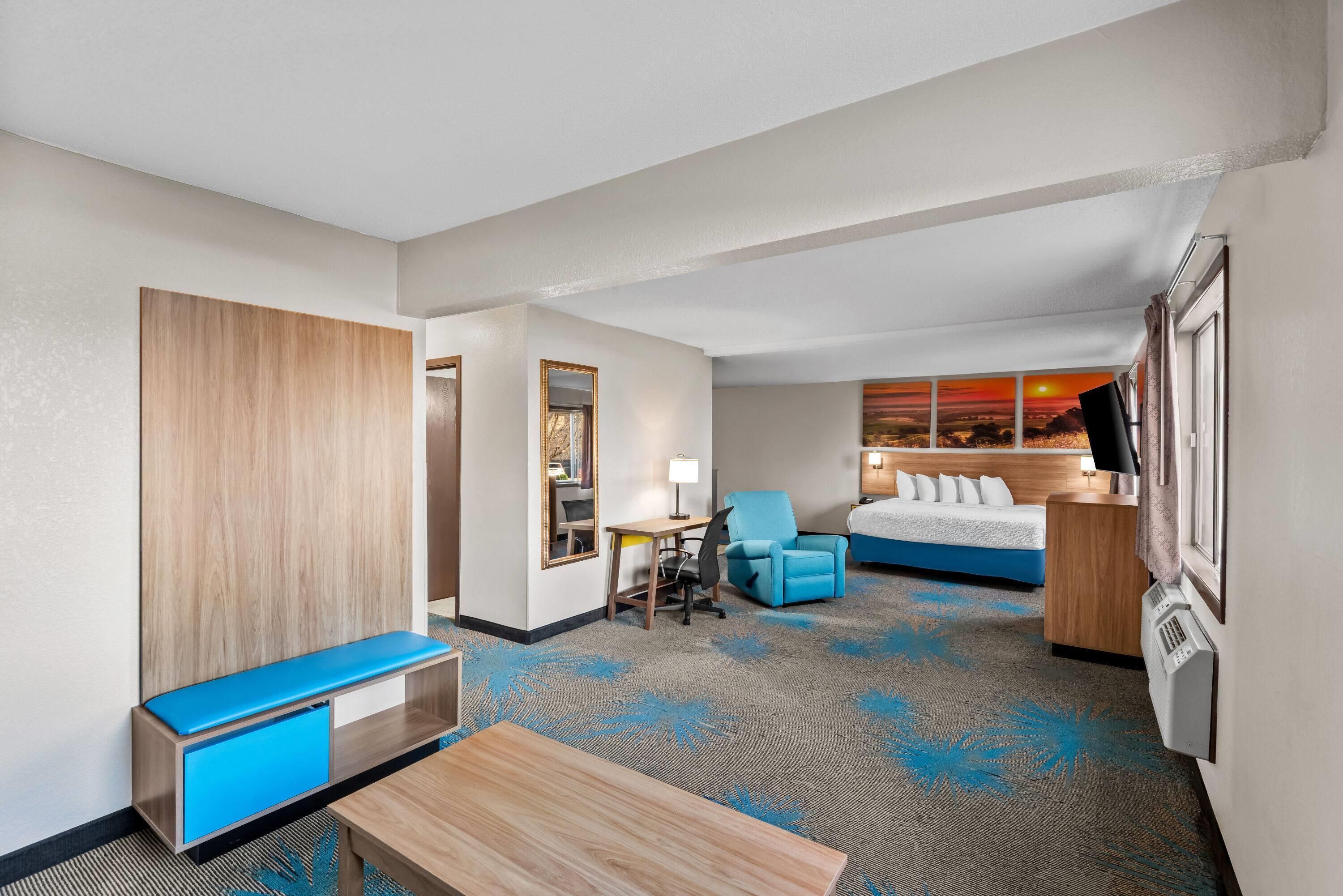 Habitación de hotel con cama, escritorio, silla, una mesita y un banco.