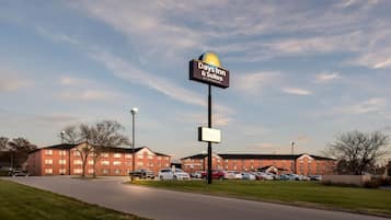 A Days Inn & Suites by Wyndham sign, a parking lot with several cars, and a building with multiple windows.