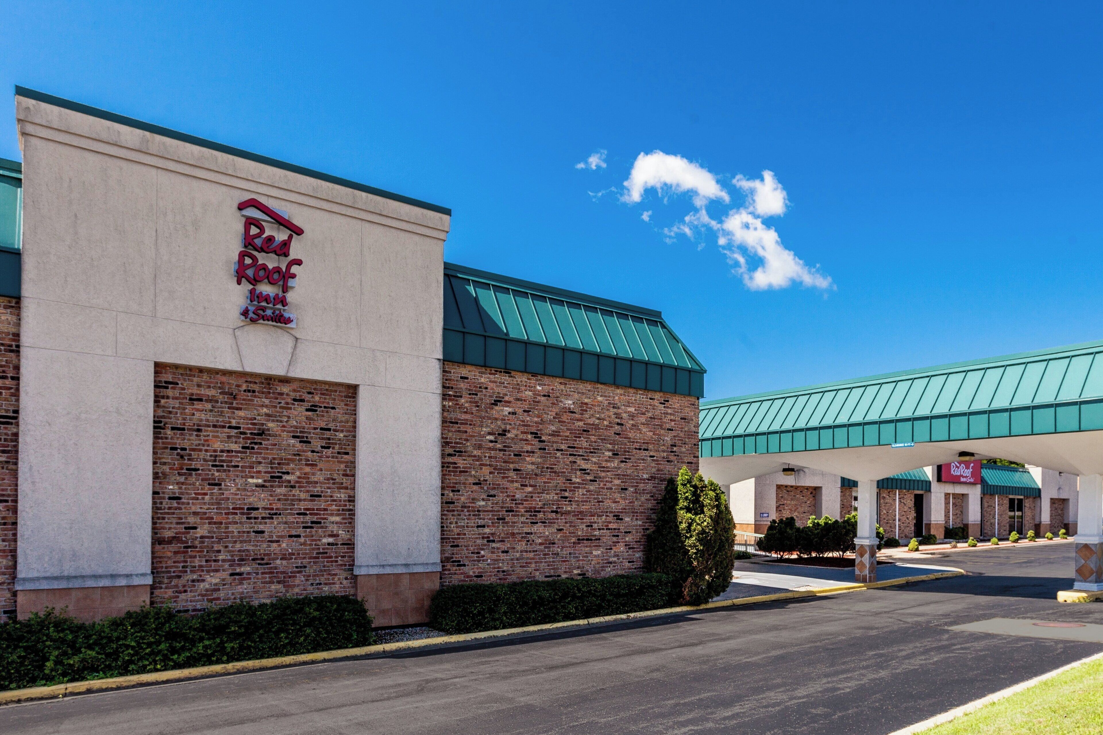 A Red Roof Inn with a brick facade and a green roof.