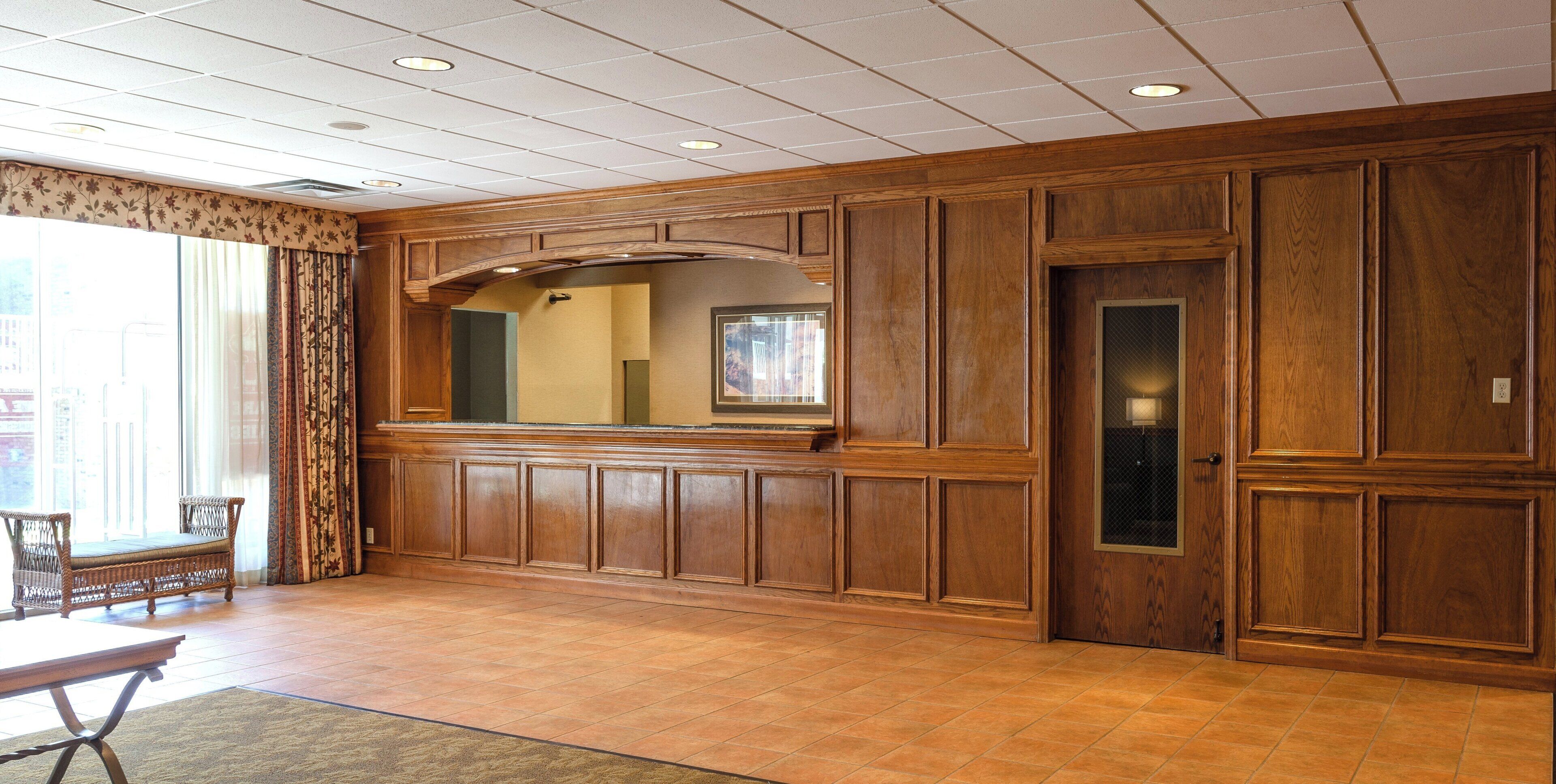 A spacious room with a large wooden panel wall, a mirror, and a door with a glass panel.