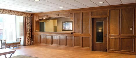 Una habitación espaciosa con un gran panel de pared de madera, un espejo y una puerta con un panel de vidrio.