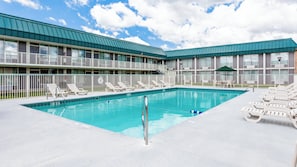 A swimming pool with lounge chairs and a building with a green roof. - Red Roof Inn & Suites DeKalb (DeKalb)