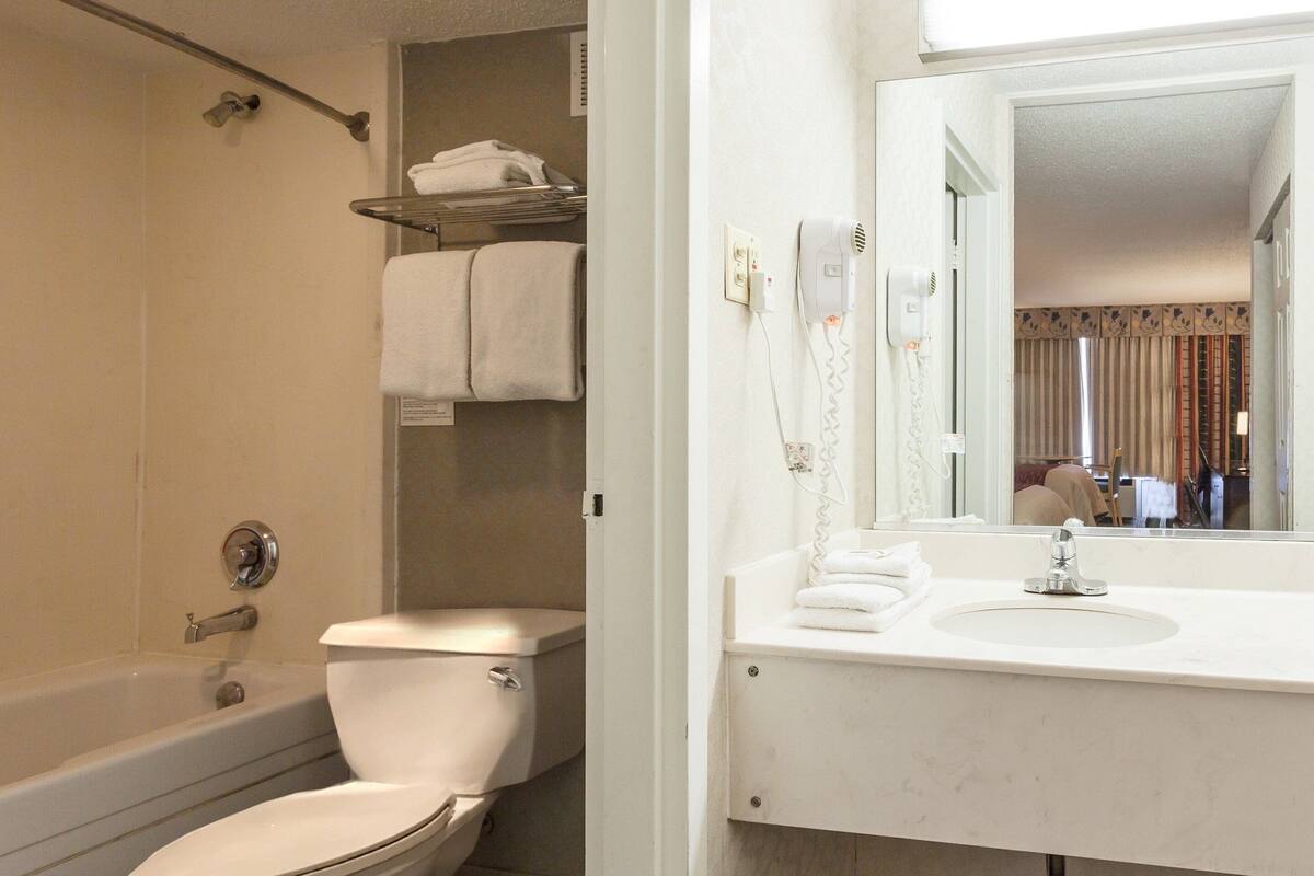 A bathroom with a bathtub, toilet, and a sink with a mirror.