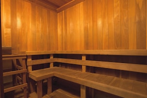 Una sauna con bancos de madera y un separador de vidrio.