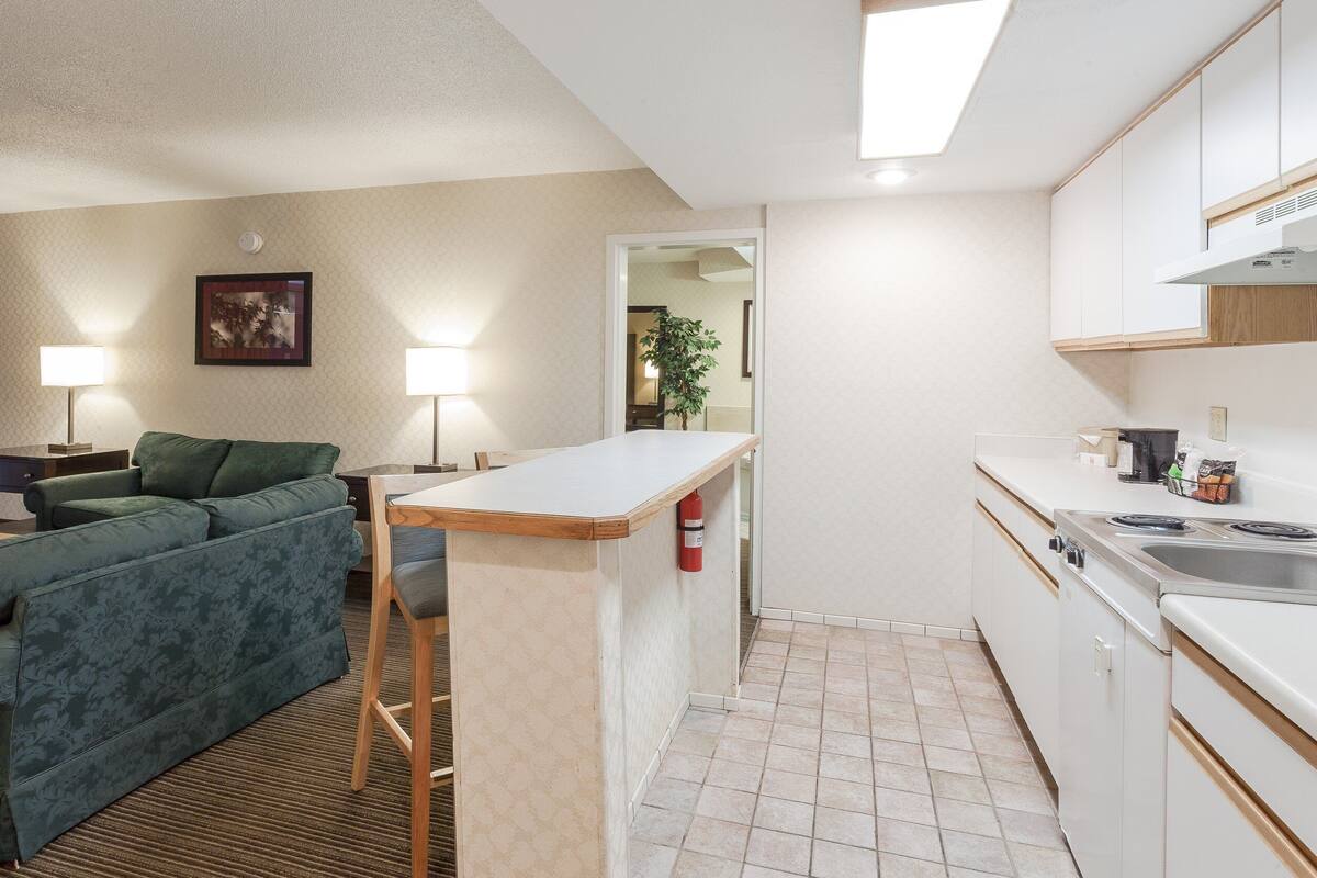 A compact living space with a sofa, a small dining table, a kitchenette, and a bathroom visible through an open door.