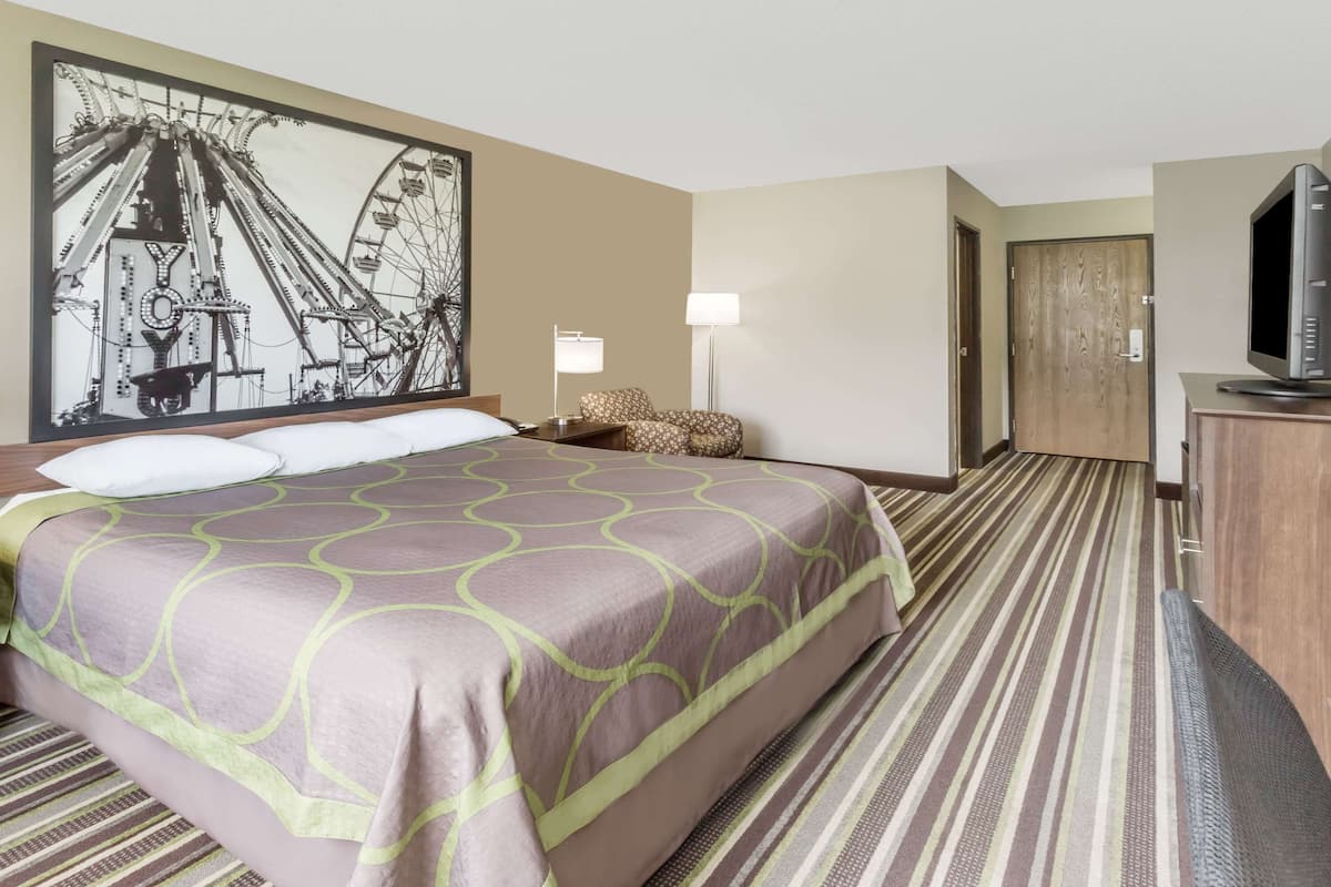 Una habitación de hotel con una cama grande, un televisor, un escritorio y una puerta.
