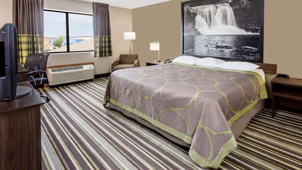 A hotel room with a large bed, a flat-screen TV, a desk, and a chair. - Super 8 by Wyndham Plymouth (Plymouth)