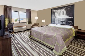 Een hotelkamer met een groot bed, een flatscreen televisie, een bureau en een stoel.