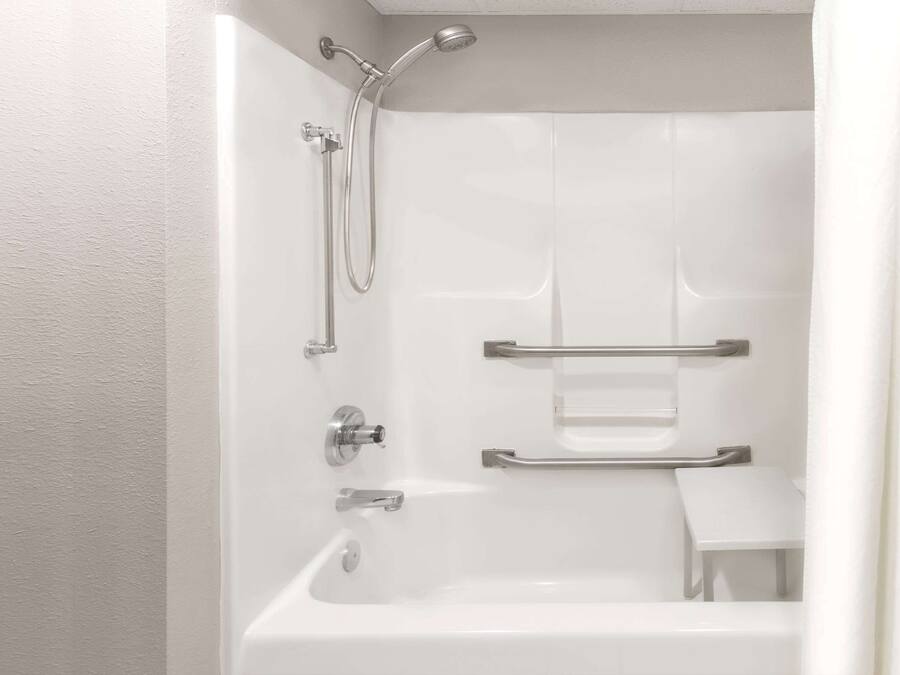 Een moderne badkamer met een inloopdouche, handgrepen en een klein bankje.