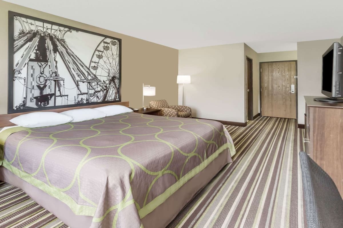 Una habitación de hotel con una cama grande, un televisor, un escritorio y una puerta.