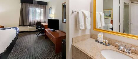 A hotel room with a bed, desk, chair, and a bathroom with a sink and mirror.
