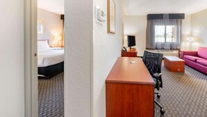 Ein Hotelzimmer mit Bett, Schreibtisch, Stuhl und einem rosa Sofa.