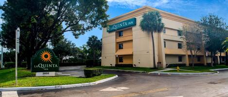 Un hotel llamado LaQuinta Inn, con un letrero, un estacionamiento y un edificio de varios pisos.