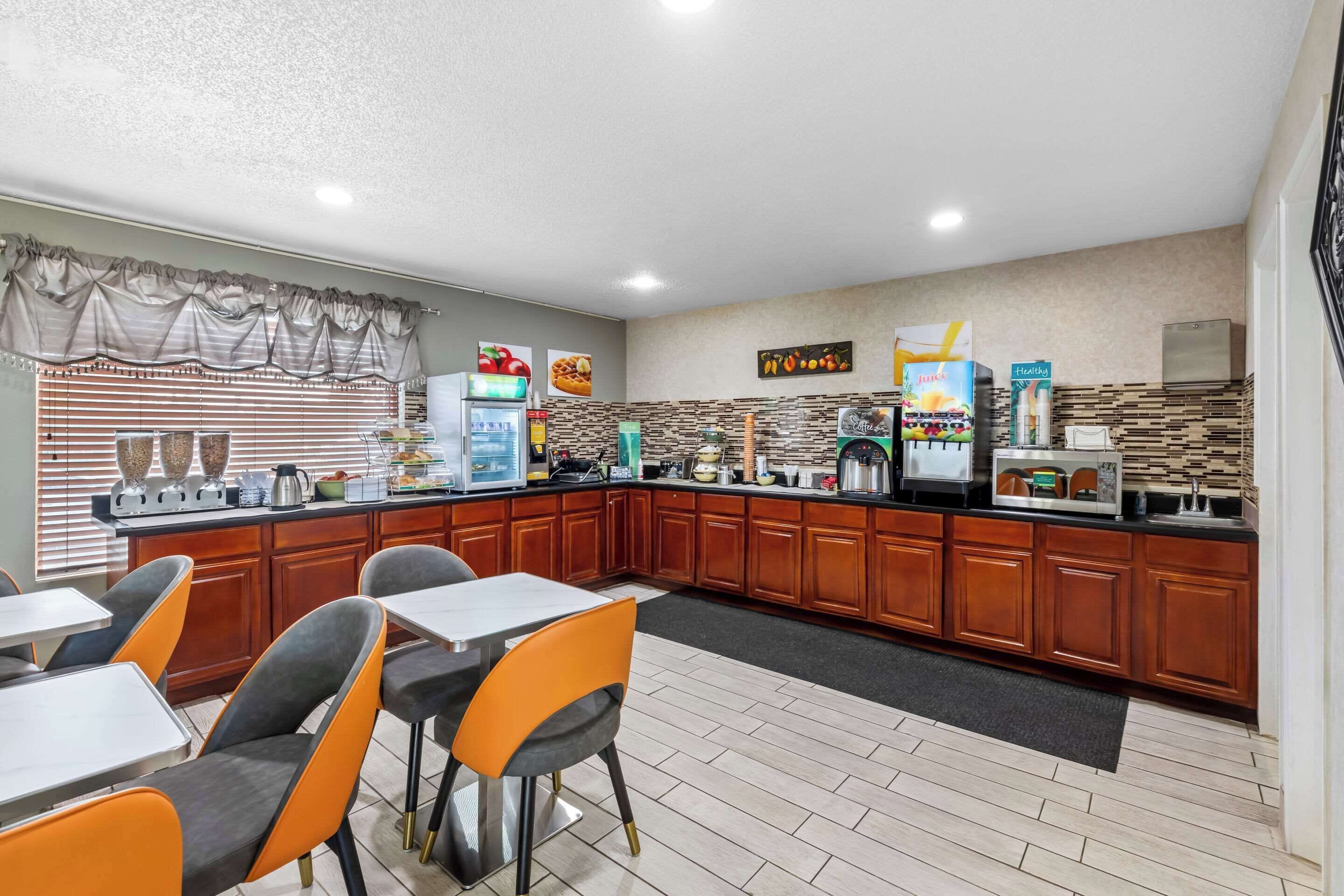 A modern kitchen with wooden cabinets, a central island, and a seating area with tables and chairs.