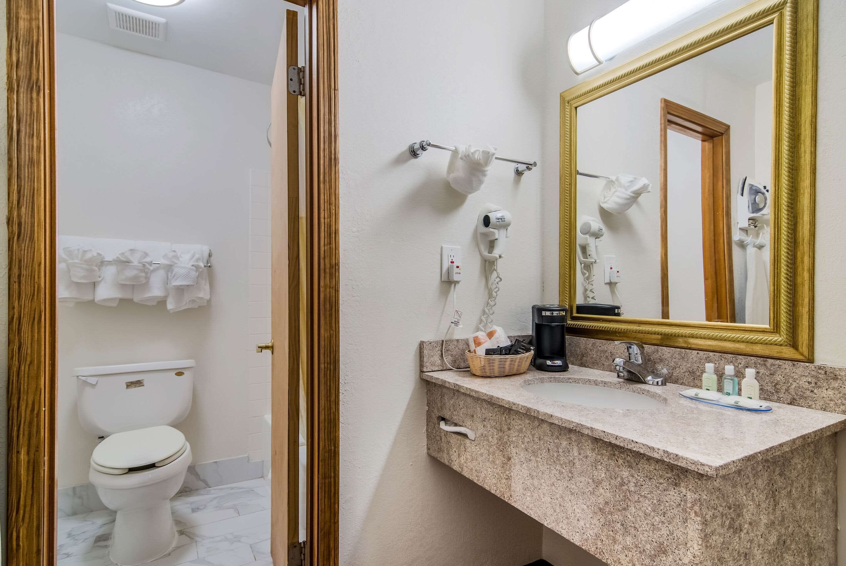 A bathroom with a toilet, a sink with a mirror, and a towel rack.