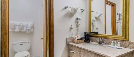 A bathroom with a toilet, a sink with a mirror, and a towel rack.