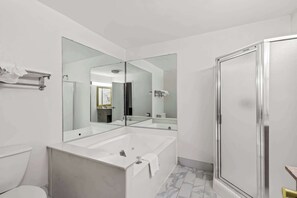 A modern bathroom with a large mirror, a bathtub, and a shower enclosure.