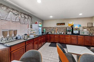 Una cocina moderna con barra libre, armarios de madera y zona de estar con mesas y sillas.