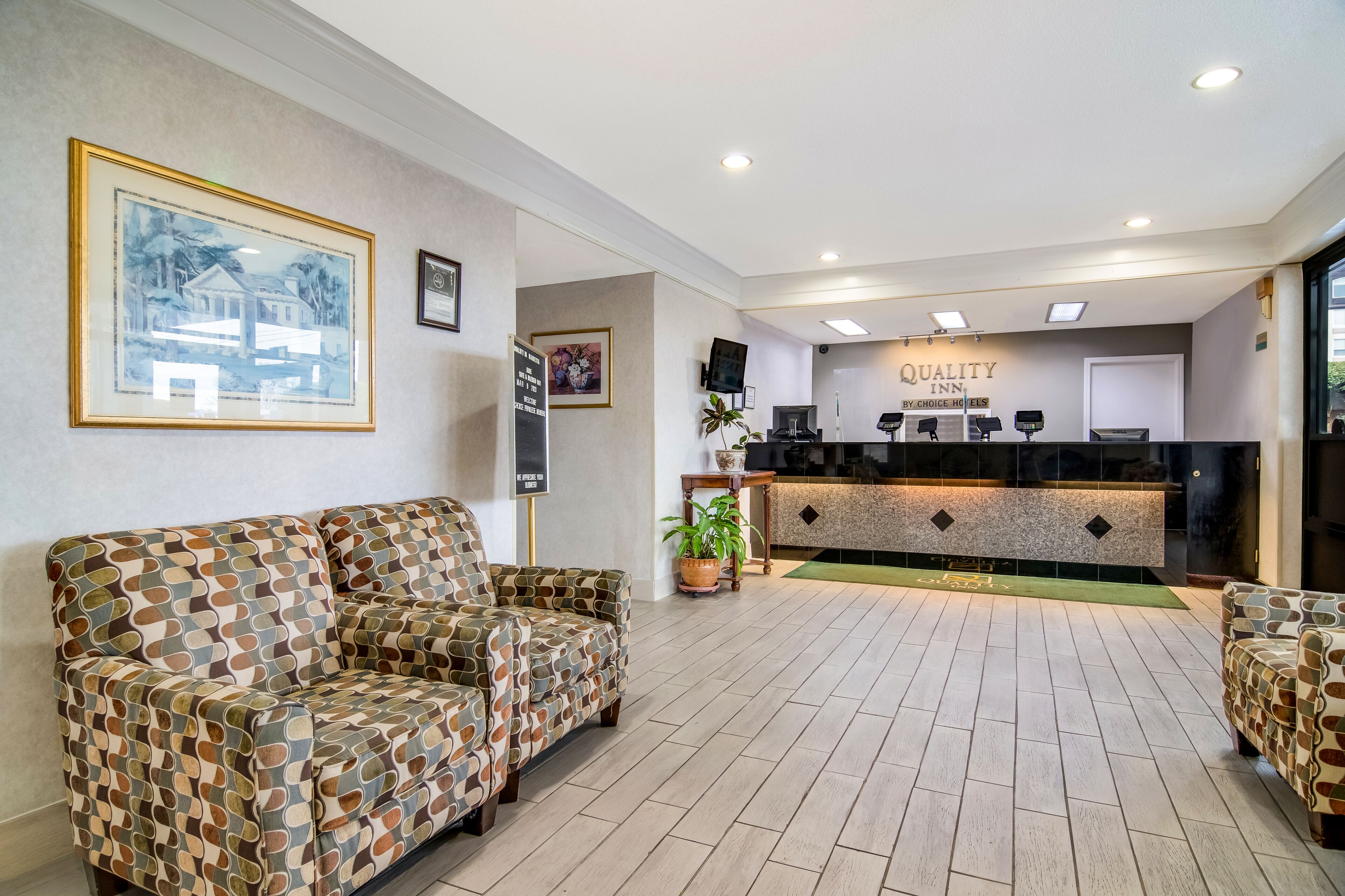 A reception area with a reception desk, framed artwork, and patterned sofas.