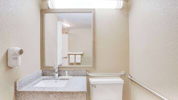 Baño con lavamanos, espejo, toallero y secador de manos.