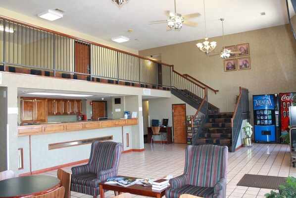 A spacious lobby with a high ceiling, a staircase, a bar area, and striped armchairs.