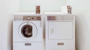 Two white Frigidaire appliances, one with a front-loading washing machine and the other with a top-loading dryer, placed side by side against a plain wall.