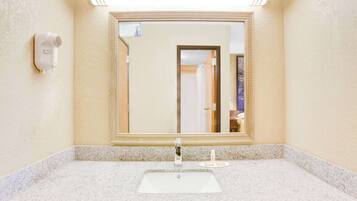 Un baño con lavabo, espejo y secador de pelo montado en la pared.