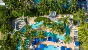 An aerial view of a resort with multiple swimming pools, palm trees, and sun loungers. - Pelican Grand Beach Resort - A Noble House Resort (Fort Lauderdale)