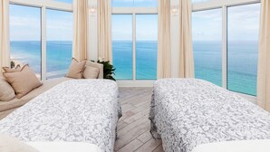 A bedroom with two beds, a view of the ocean, and a large window with curtains. - Pelican Grand Beach Resort - A Noble House Resort (Fort Lauderdale)