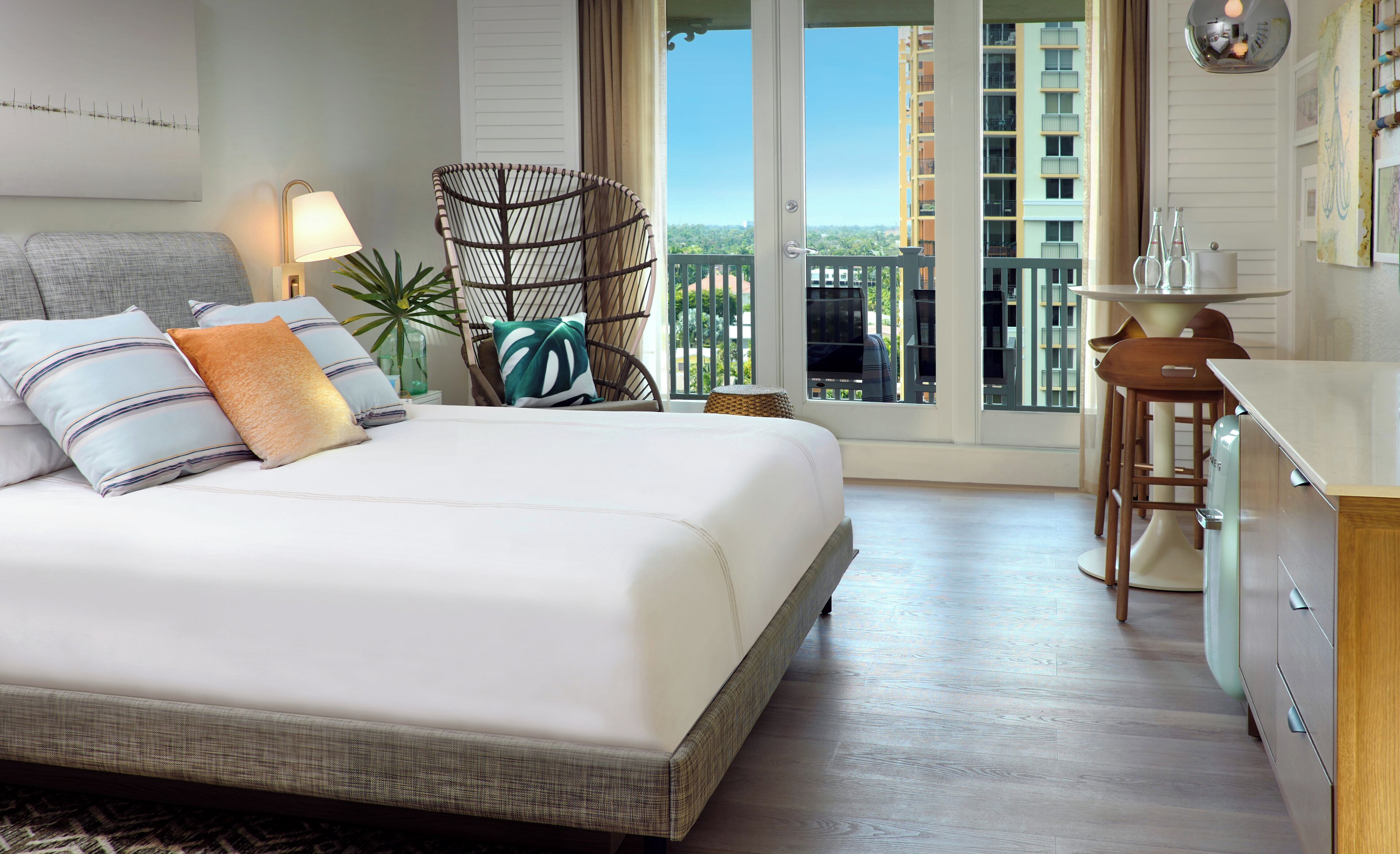 A hotel room with a bed, a chair, a desk, and a view of a building through the window.