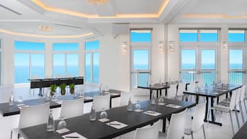Ein geräumiger Essbereich mit großen Fenstern und Meerblick, eleganten Kronleuchtern und modernen Tischdekorationen.