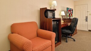 A hotel room with a single orange armchair, a desk with a computer and a television, and a door. - Red Roof Inn Dalton (Dalton)