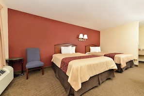 A hotel room with two beds, a chair, a table, and a wall-mounted lamp. - Red Roof Inn Dalton (Dalton)