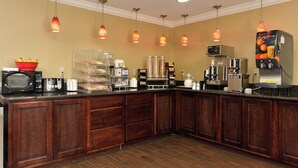 A hotel kitchen with a buffet setup, including a microwave, toaster, and coffee machine. - Red Roof Inn Dalton (Dalton)