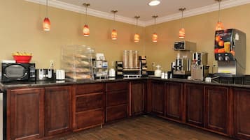 A hotel kitchen with a buffet setup, including a microwave, toaster, and coffee machine.