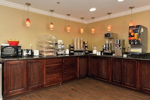 A hotel kitchen with a buffet setup, including a microwave, toaster, and coffee machine. - Red Roof Inn Dalton (Dalton)