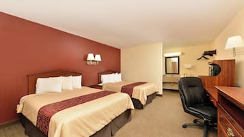 Ein Hotelzimmer mit zwei Betten, einem Schreibtisch, einem Stuhl und einem durch eine offene Tür einsehbaren Badezimmer.